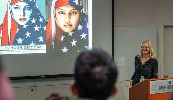 Professor Kimberly Segall presents on her book Superheroes in the Streets, displaying a photo of a women in a stars-and-stripes hijab